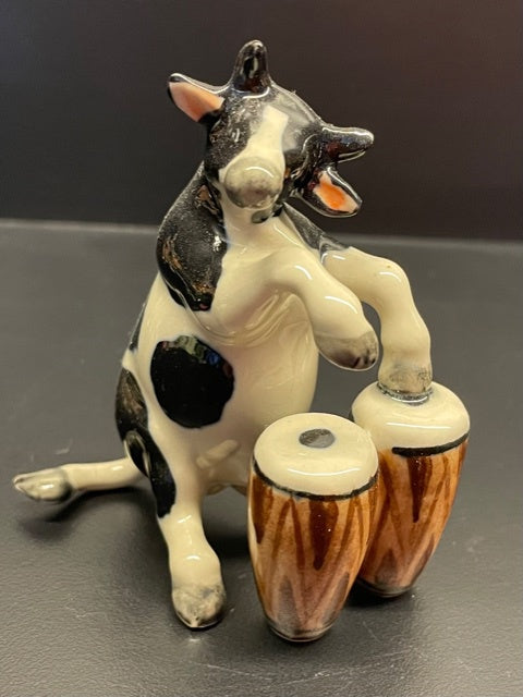 Porcelain Cow Playing the Bongos.